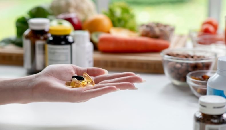 Mano de Mujer Sosteniendo Capsulas de Suplementos