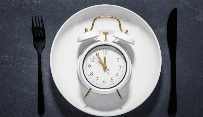Imagen de Reloj Dentro de un Plato Blanco Dispuesto a Manera de Servicio de Mesa junto a Tenedor y Cuchillo
